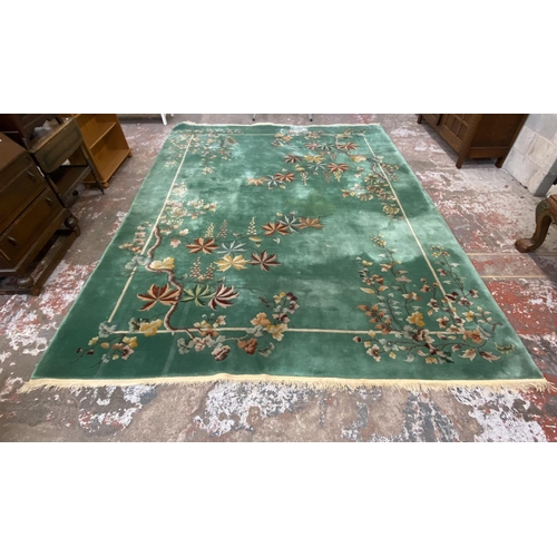 54 - A mid/late 20th century Chinese machine woven green ground floral pattern rug - approx. 395cm x 304c... 