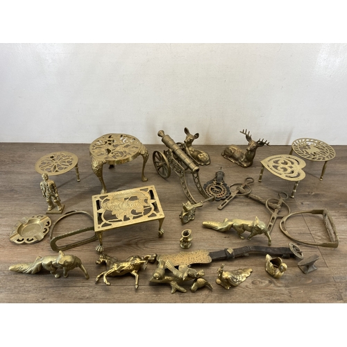 620 - A collection of brassware to include trivet stands, cannon ornament, deer figurine, pair of stirrups... 