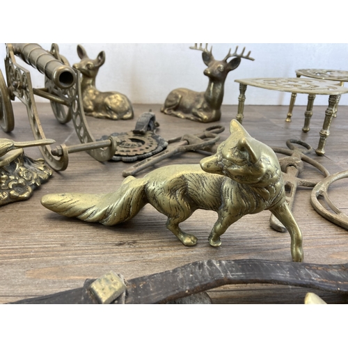 620 - A collection of brassware to include trivet stands, cannon ornament, deer figurine, pair of stirrups... 