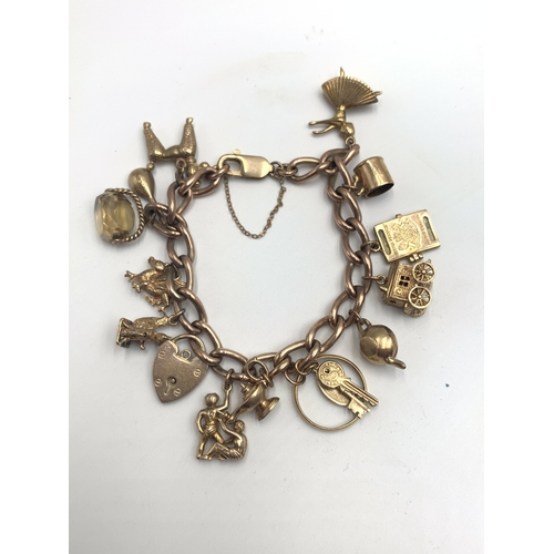 2148 - A 9ct gold charm bracelet with heart shaped padlock clasp and fourteen charms, one 22ct gold wedding...
