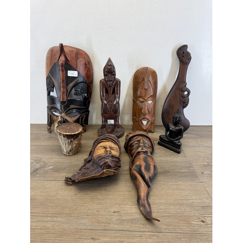 1051 - Eight ethnographical items to include two leather wall masks, hand carved hardwood wall mask made in... 