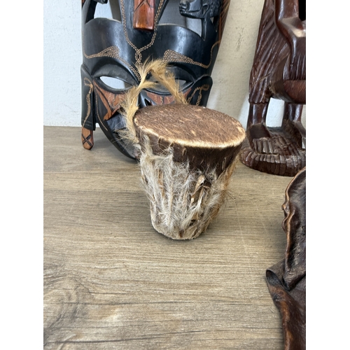 1051 - Eight ethnographical items to include two leather wall masks, hand carved hardwood wall mask made in... 