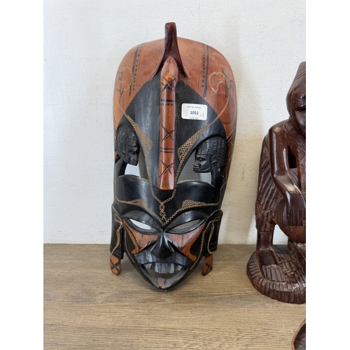 1051 - Eight ethnographical items to include two leather wall masks, hand carved hardwood wall mask made in... 