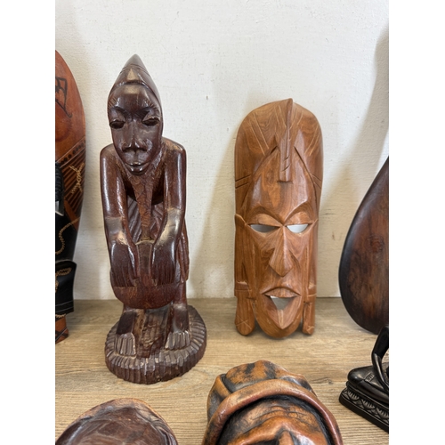 1051 - Eight ethnographical items to include two leather wall masks, hand carved hardwood wall mask made in... 