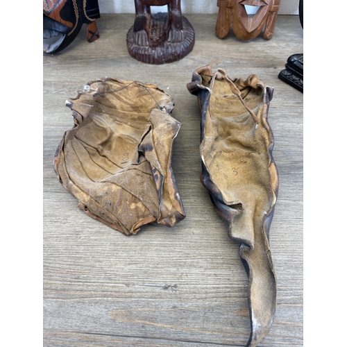 1051 - Eight ethnographical items to include two leather wall masks, hand carved hardwood wall mask made in... 