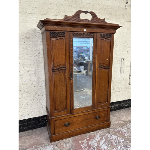 1002 - An early 20th century carved oak mirror door wardrobe - approx. 213cm high x 134cm wide x 52cm deep
