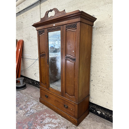 1002 - An early 20th century carved oak mirror door wardrobe - approx. 213cm high x 134cm wide x 52cm deep