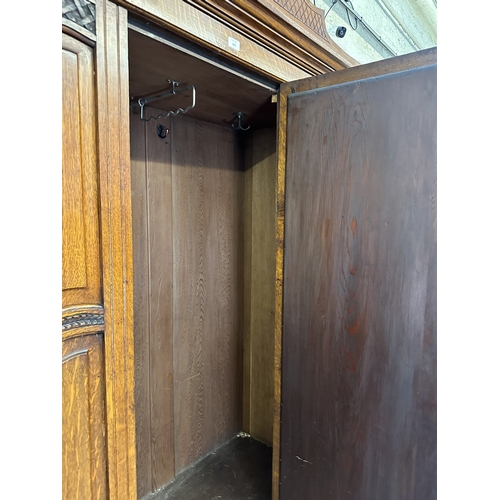 1002 - An early 20th century carved oak mirror door wardrobe - approx. 213cm high x 134cm wide x 52cm deep
