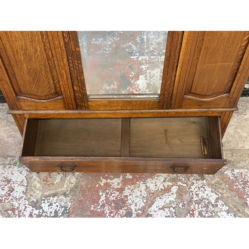 1002 - An early 20th century carved oak mirror door wardrobe - approx. 213cm high x 134cm wide x 52cm deep