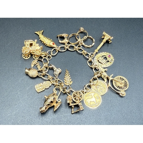A 9ct gold charm bracelet with nineteen charms, six yellow metal, one 8ct, ten 9ct, one 12ct gold filled and one 14ct  - approx. gross weight 49g