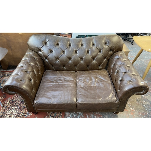 32 - A brown leather Chesterfield two seater sofa - approx. 92cm high x 175cm wide x 105cm deep