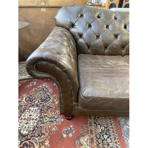 32 - A brown leather Chesterfield two seater sofa - approx. 92cm high x 175cm wide x 105cm deep