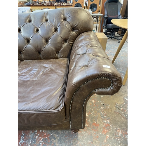 32 - A brown leather Chesterfield two seater sofa - approx. 92cm high x 175cm wide x 105cm deep