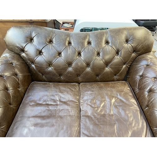 32 - A brown leather Chesterfield two seater sofa - approx. 92cm high x 175cm wide x 105cm deep