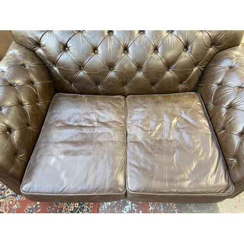 32 - A brown leather Chesterfield two seater sofa - approx. 92cm high x 175cm wide x 105cm deep