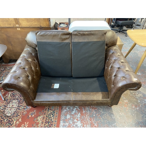 32 - A brown leather Chesterfield two seater sofa - approx. 92cm high x 175cm wide x 105cm deep