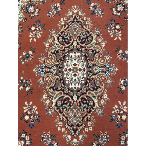 34 - A Persian style machine woven red ground rug - approx. 230cm x 162cm