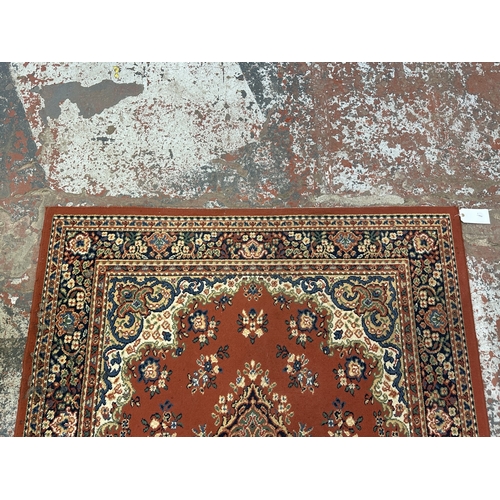 34 - A Persian style machine woven red ground rug - approx. 230cm x 162cm