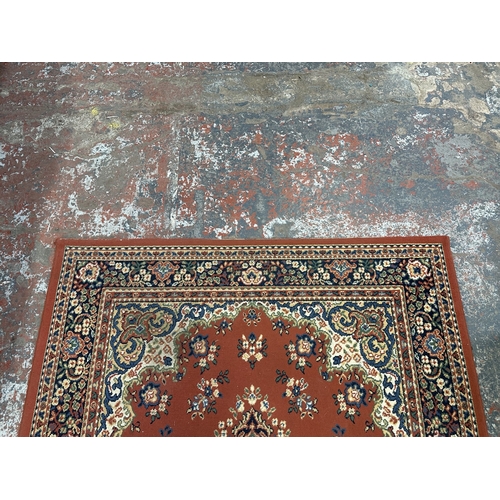 34 - A Persian style machine woven red ground rug - approx. 230cm x 162cm