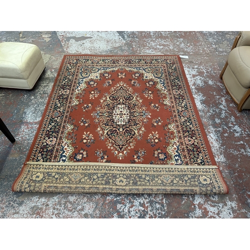 34 - A Persian style machine woven red ground rug - approx. 230cm x 162cm