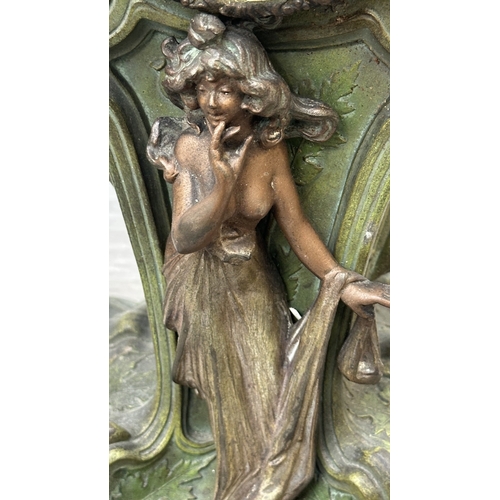 107 - An Art Nouveau French cast metal figural mantel clock with hand painted enamel face and foliate deco... 