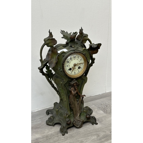 107 - An Art Nouveau French cast metal figural mantel clock with hand painted enamel face and foliate deco... 