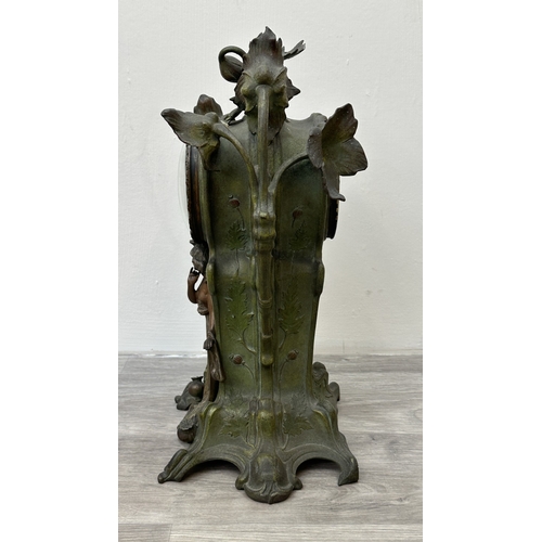 107 - An Art Nouveau French cast metal figural mantel clock with hand painted enamel face and foliate deco... 