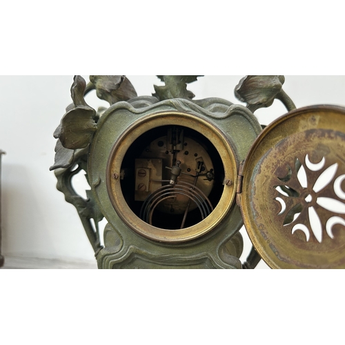 107 - An Art Nouveau French cast metal figural mantel clock with hand painted enamel face and foliate deco... 
