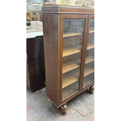 13B - A 1920s/30s oak glazed bookcase on baluster supports - approx. 149cm high x 95cm wide x 30cm deep