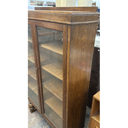 13B - A 1920s/30s oak glazed bookcase on baluster supports - approx. 149cm high x 95cm wide x 30cm deep
