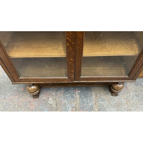 13B - A 1920s/30s oak glazed bookcase on baluster supports - approx. 149cm high x 95cm wide x 30cm deep