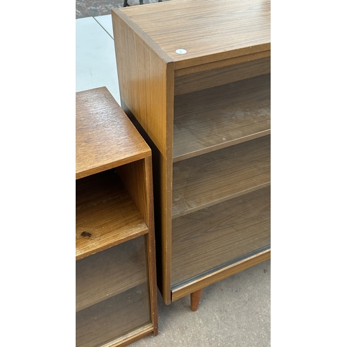 13D - A mid 20th century teak effect bookcase with two glass sliding doors - approx. 100cm high x 130cm wi... 