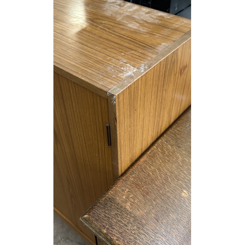 13D - A mid 20th century teak effect bookcase with two glass sliding doors - approx. 100cm high x 130cm wi... 