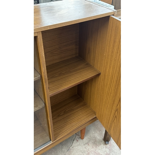 13D - A mid 20th century teak effect bookcase with two glass sliding doors - approx. 100cm high x 130cm wi... 
