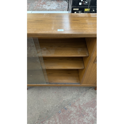 13D - A mid 20th century teak effect bookcase with two glass sliding doors - approx. 100cm high x 130cm wi... 