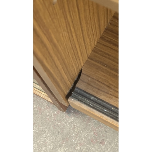 13D - A mid 20th century teak effect bookcase with two glass sliding doors - approx. 100cm high x 130cm wi... 