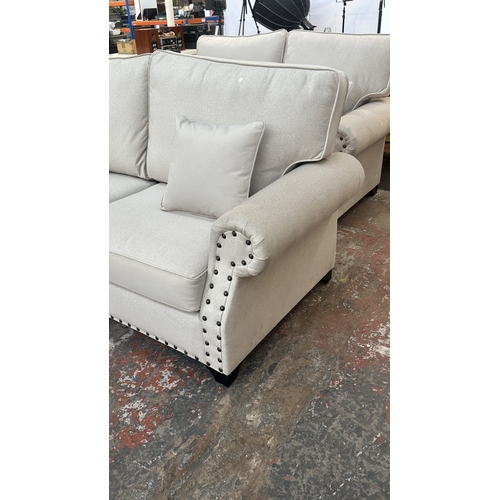 16 - A modern grey fabric upholstered and metal studded two piece lounge suite comprising two seater sofa... 