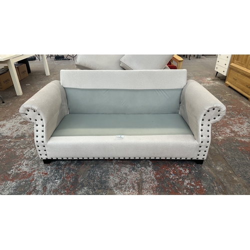 16 - A modern grey fabric upholstered and metal studded two piece lounge suite comprising two seater sofa... 