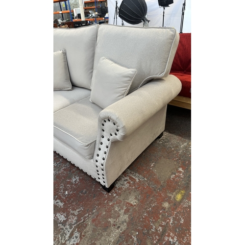 16 - A modern grey fabric upholstered and metal studded two piece lounge suite comprising two seater sofa... 