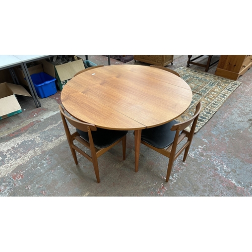37C - A mid 20th century Elliotts of Newbury teak circular drop leaf dining table and four black vinyl cha... 
