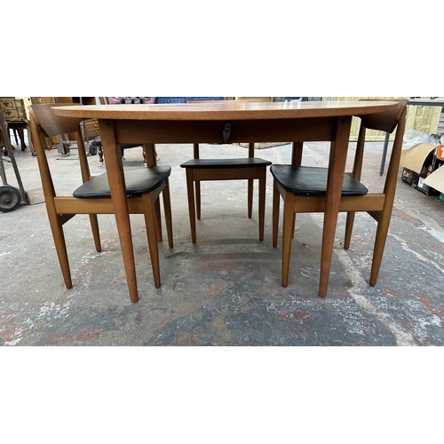 37C - A mid 20th century Elliotts of Newbury teak circular drop leaf dining table and four black vinyl cha... 