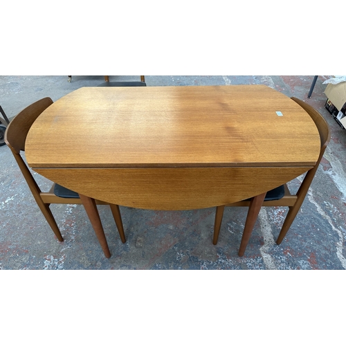 37C - A mid 20th century Elliotts of Newbury teak circular drop leaf dining table and four black vinyl cha... 