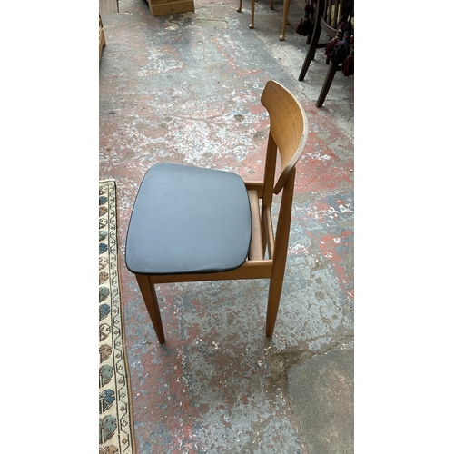 37C - A mid 20th century Elliotts of Newbury teak circular drop leaf dining table and four black vinyl cha... 