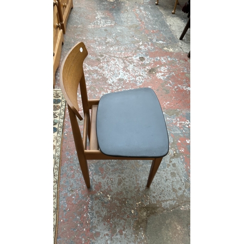 37C - A mid 20th century Elliotts of Newbury teak circular drop leaf dining table and four black vinyl cha... 