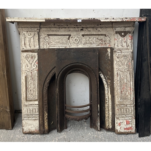 48 - A Victorian white painted cast iron fire surround with two inserts - approx. 126cm high x 136cm wide... 