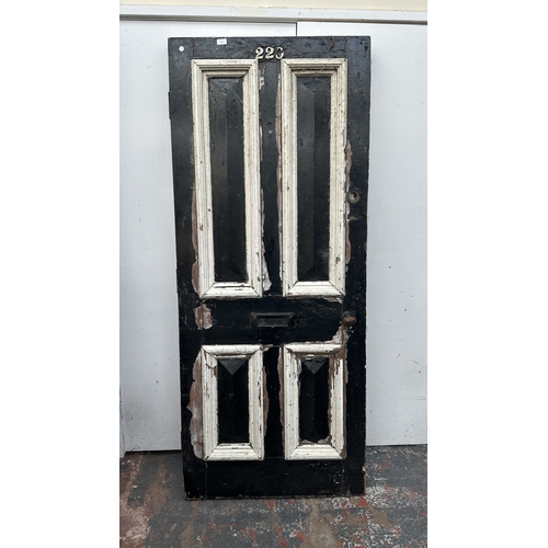 56 - A Victorian black and white painted wooden four panel door - approx. 195cm high x 81cm wide