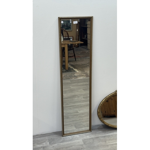 63E - Two gilt framed wall mirrors, one oval - approx. 49cm high x 71cm wide and one rectangular - approx.... 