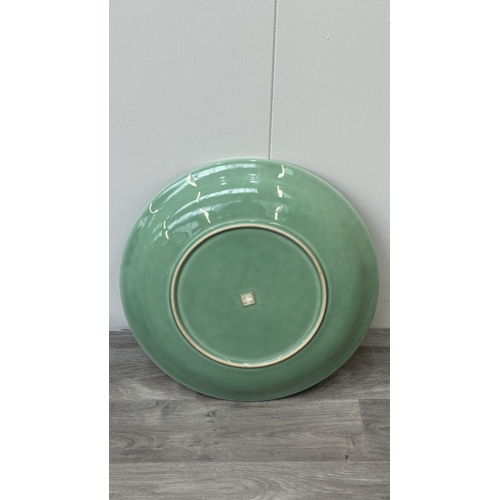 89 - A Chinese celadon glazed ceramic charger with dragon motif on carved wooden stand - approx. 50cm dia... 