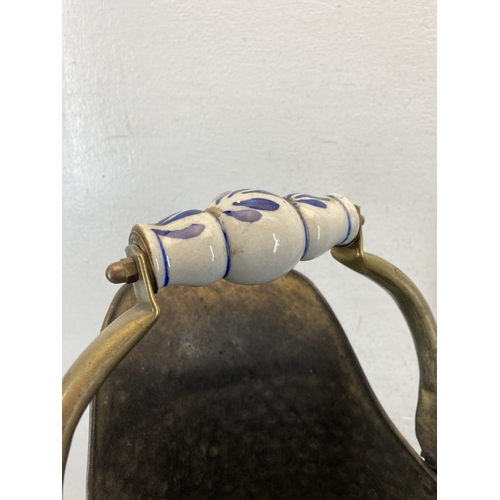 346 - A hammered brass coal scuttle with ceramic handle and three fireside accessories