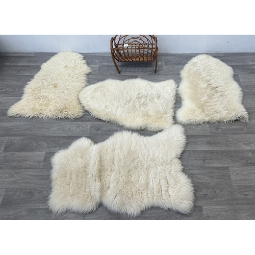 126 - Five items, one mid 20th century bamboo and rattan magazine rack and four sheepskin rugs, two Creati... 